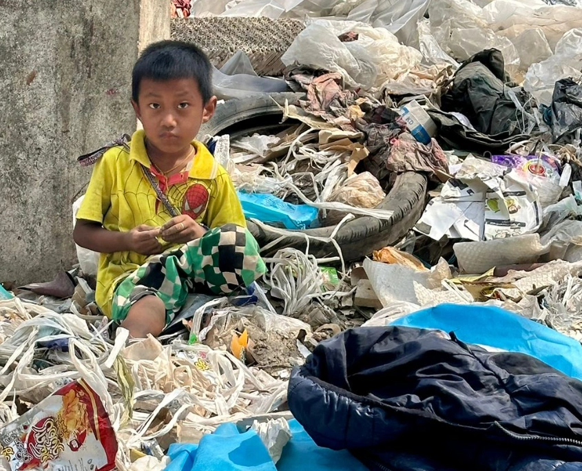 Ein Straßenkind in Yangon, im Müll sitzend gibt es keinen Schutz vor der Gluthitze